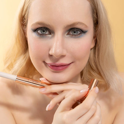 A woman wearing and presenting Oplenza's Hydrating Shimmer smooth Lip Balm in shade Bombshell