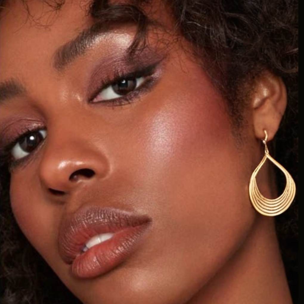 Woman wearing and showcasing the effect of oplenza opulent Light Luminizer in shade Bravura