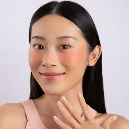 A woman wearing on her cheek Oplenza highly pigmented, bold color dewy Blush Stick in shade Brighten