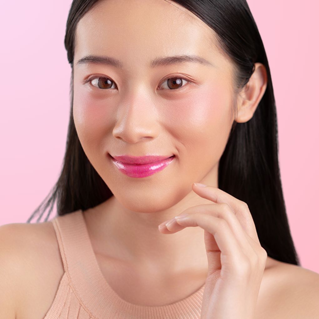 A woman wearing and showcasing the best cruelty-free, vegan, shiny and hydrating lip gloss in shade Candy