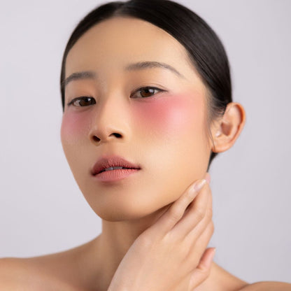 A woman wearing on her cheek Oplenza highly pigmented, bold color dewy Blush Stick in shade Cheer