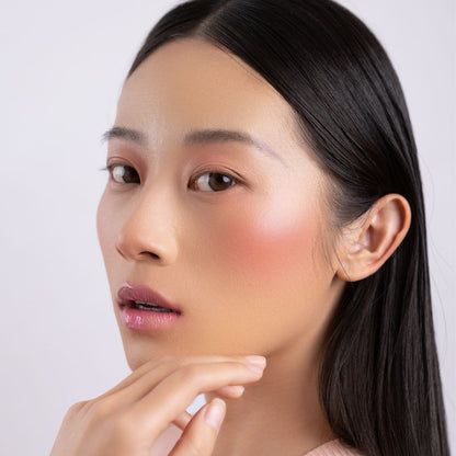A woman wearing on her cheek Oplenza highly pigmented, bold color dewy Blush Stick in shade Cherish