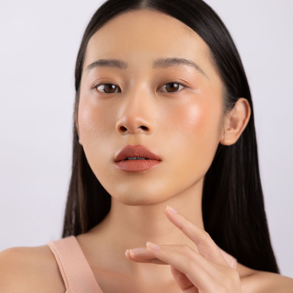 A woman wearing on her cheek Oplenza highly pigmented, bold color dewy Blush Stick in shade Ease