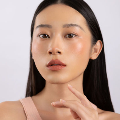 A woman wearing on her cheek Oplenza highly pigmented, bold color dewy Blush Stick in shade Ease