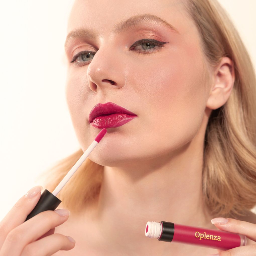 A Woman wearing and showcasing the elegant and luxury Oplenza Signature Velvet Liquid Lipstick in the color Fuschsia Silk