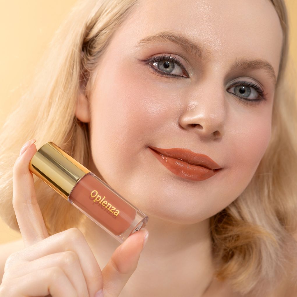 A woman wearing and showcasing the best cruelty-free, vegan, shiny and hydrating lip gloss in shade Peach Nectar