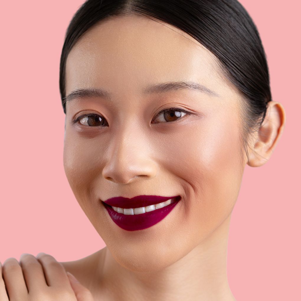 Model wearing and showcasing the bold color of the vegan, cruelty-free Oplenza matte liquid lipstick in the shade Rouge Royale