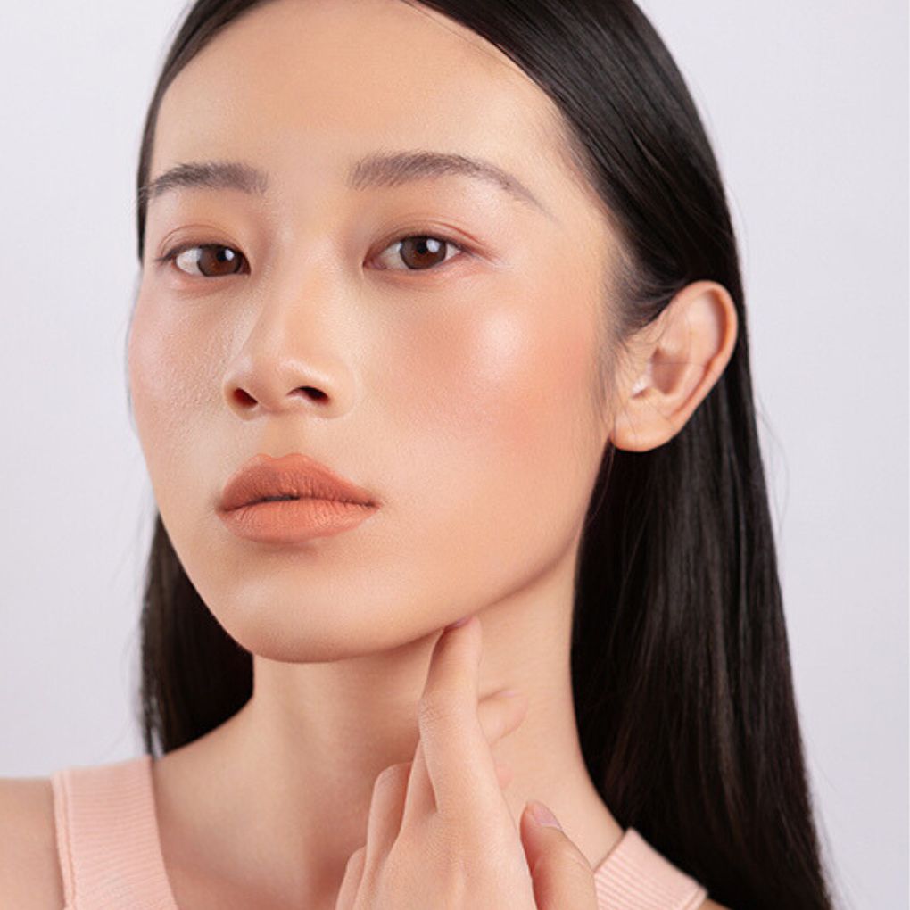 Model wearing and showcasing the bold color of the vegan, cruelty-free Oplenza matte liquid lipstick in the shade Solace