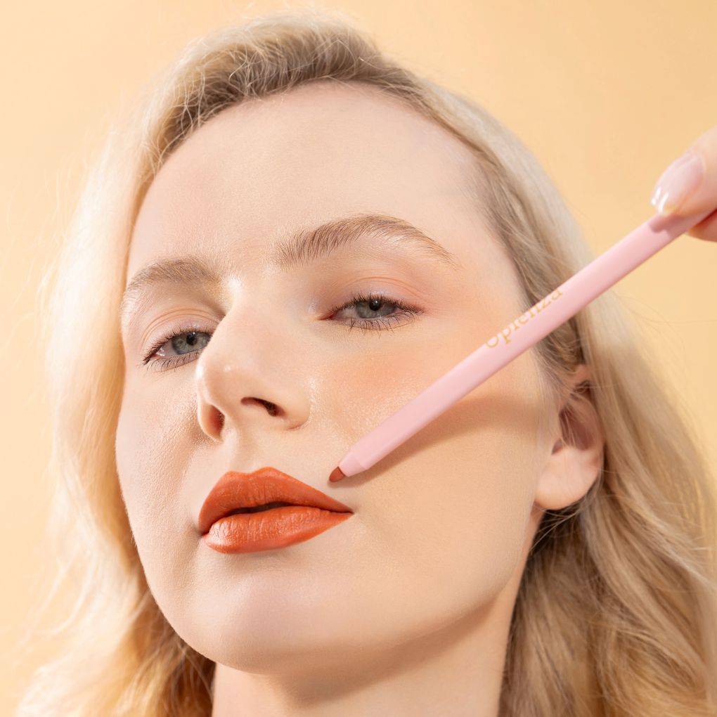 An elegant woman wearing and showcasing the vegan, luxury and cruelty free oplenza Define & Refine Lip Liner in the color Terracotta Kiss