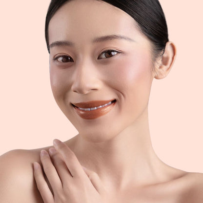 A woman wearing and showcasing the best cruelty-free, vegan, shiny and hydrating lip gloss in shade Toffee
