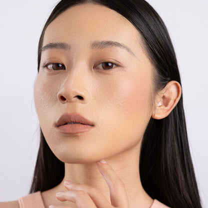 A Woman wearing and showcasing the effect of the elegant cruelty free Oplenza Signature Velvet Liquid Lipstick in the color Vlevet Nude