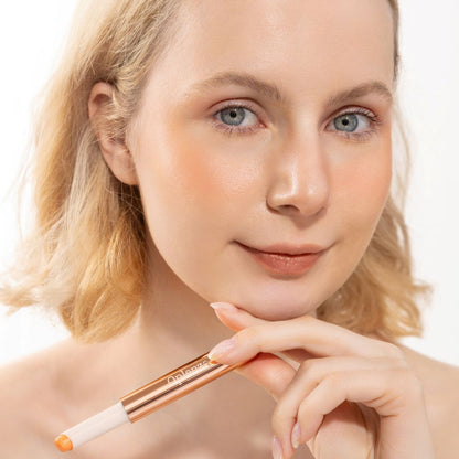 A woman wearing and presenting Oplenza's Hydrating Shimmer Luminous Lip Balm in shade Afterglow