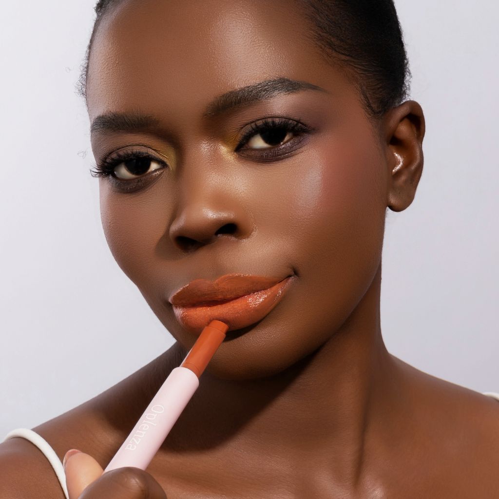 Woman wearing and presenting Oplenza Hydrating Dewy Lip Balm in shade Peachie, vegan hydrating lip care with natural glossy finish